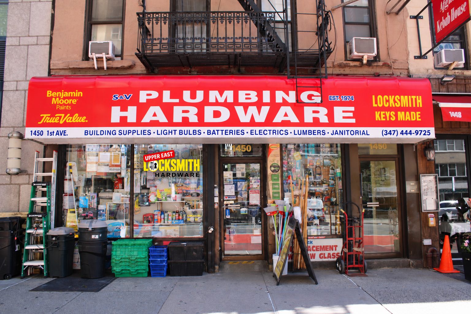 S&V Plumbing Hardware storefront at 1450 1st Ave with the Upper East Locksmith sign in the window
